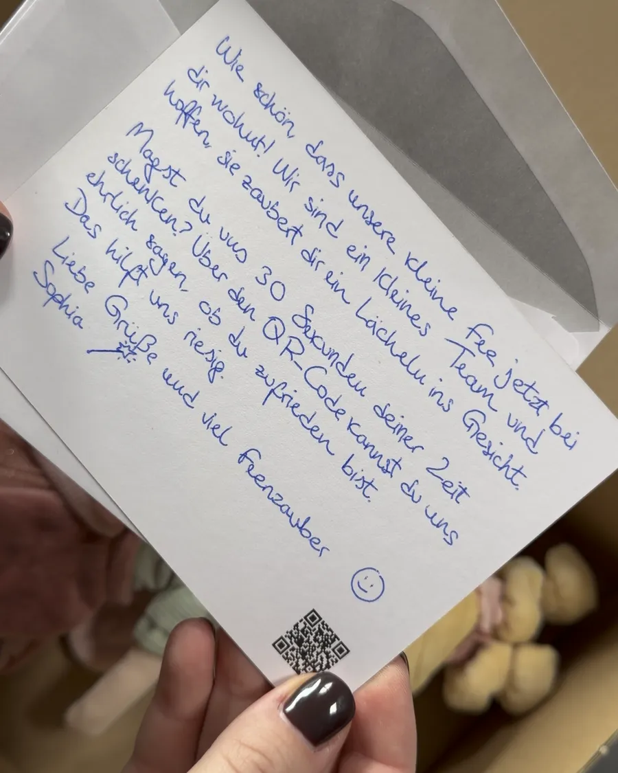 Handgeschriebene Karte mit QR-Code wird aus dem Umschlag gezogen