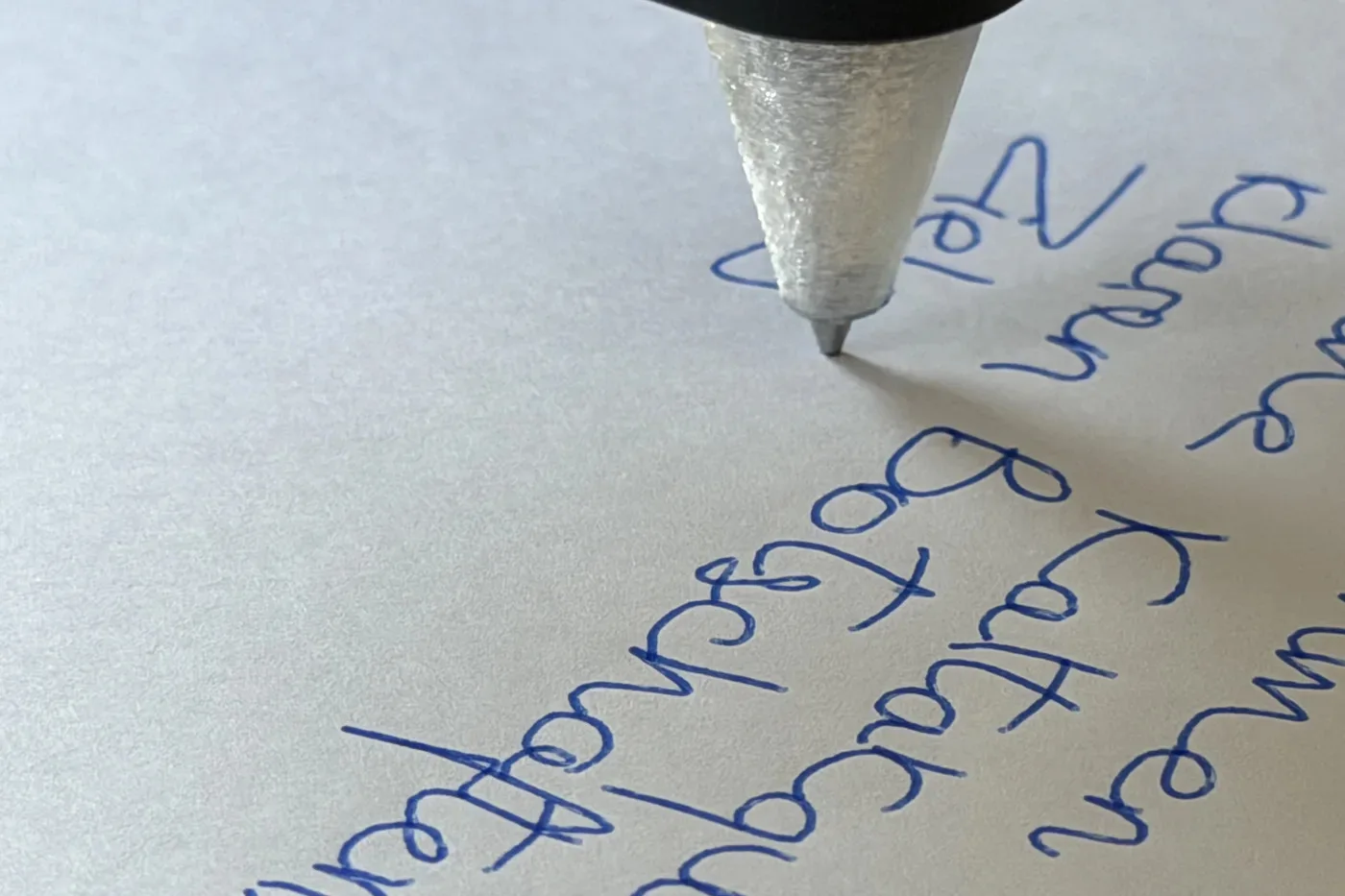 Nahaufnahme einer Kugelschreiberspitze, die blaue Handschrift auf Papier schreibt